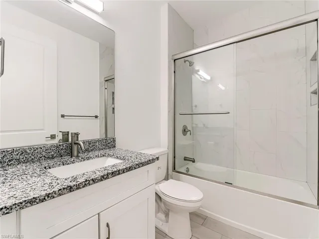 Bathroom with combined bath / shower with glass door and vanity