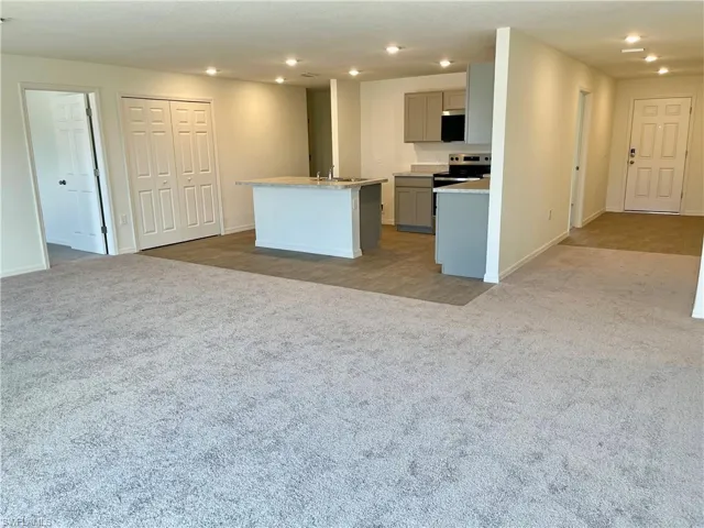 Kitchen with gray cabinets, recessed lighting, open floor plan, and light colored carpet