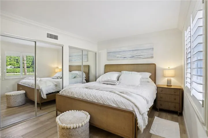 Bedroom featuring two closets, hardwood / wood-style flooring, and ornamental molding
