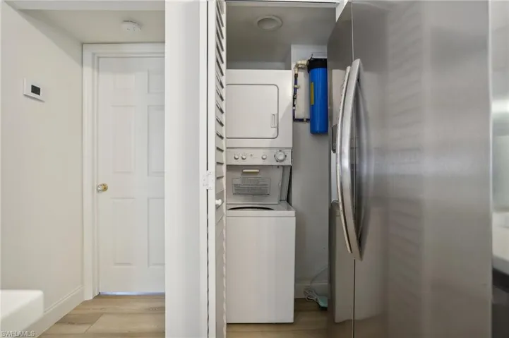 Laundry area featuring stacked washing maching and dryer and light hardwood / wood-style floors