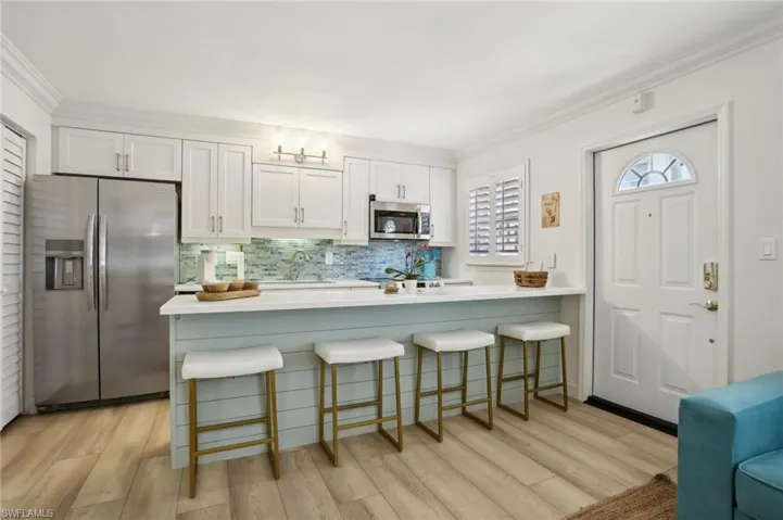 Kitchen with sink, stainless steel appliances, light wood-type flooring, and white cabinetry