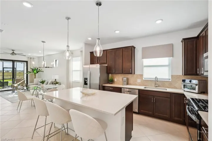 Kitchen with sink, hanging light fixtures, ceiling fan, a kitchen island, and stainless steel appliances