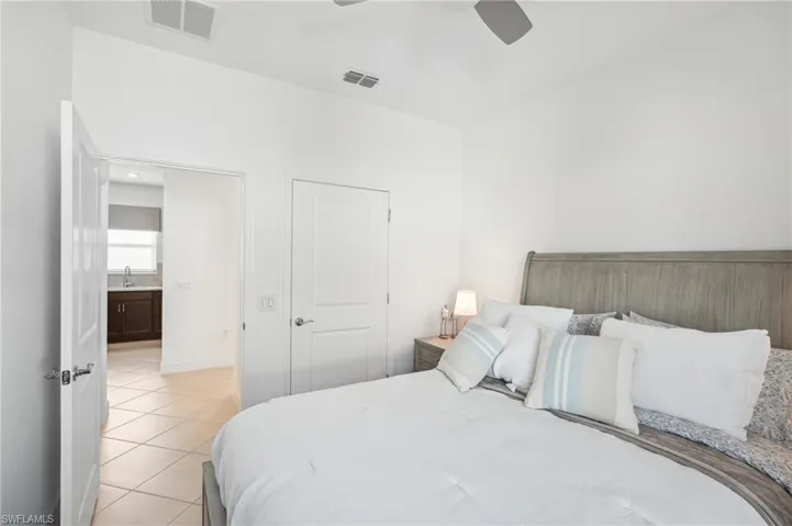 Bedroom with ceiling fan, light tile patterned floors, sink, and a closet