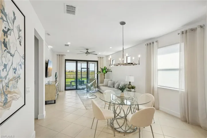 Dining room with light tile patterned floors and ceiling fan with notable chandelier