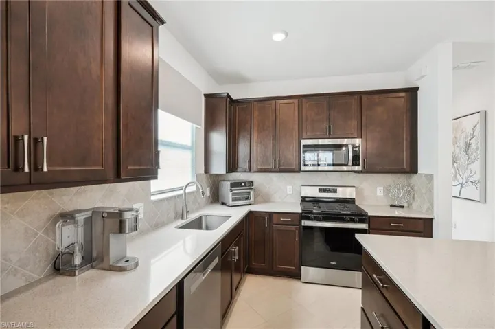 Kitchen with dark brown cabinetry, sink, and stainless steel appliances
