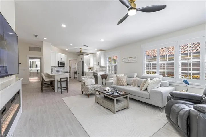 Living room with recessed lighting, vaulted ceiling, ceiling fan, light wood-style flooring, and a fireplace