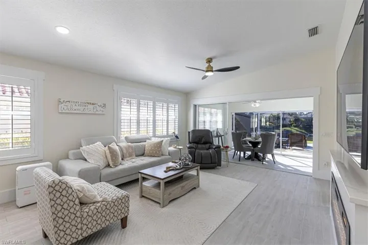 Living area with plenty of natural light, a sunroom, a textured ceiling, light wood-type flooring, and vaulted ceiling