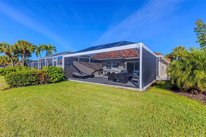 Rear view of property featuring glass enclosure, a yard, and a sunroom