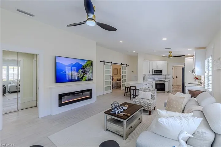 Living area with plenty of natural light, a ceiling fan, a barn door, a glass covered fireplace, and recessed lighting