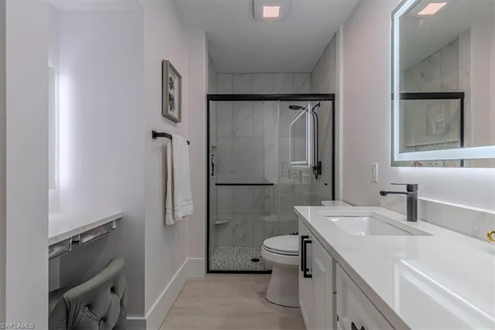 Bathroom featuring vanity, a marble finish shower, and wood tiled floors