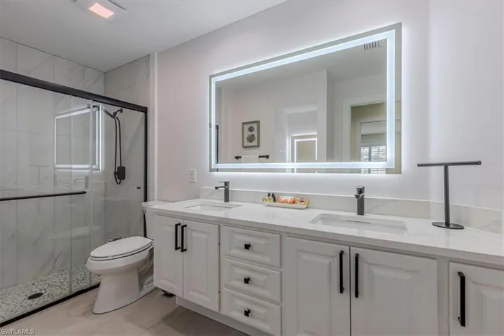 Bathroom with double vanity and a marble finish shower