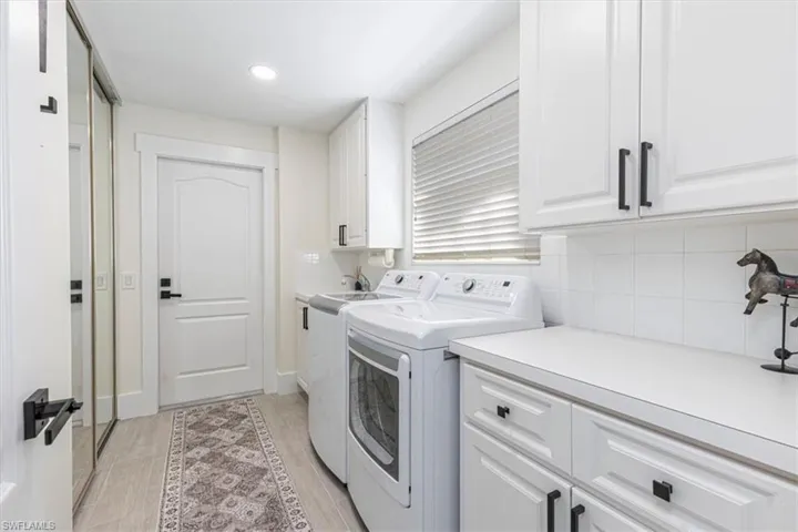 Washroom with washer and clothes dryer, cabinet space, and wood finish floors