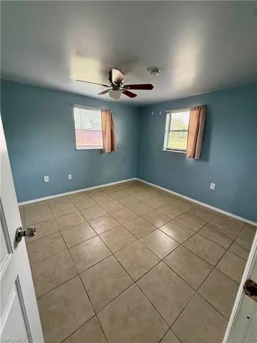 Unfurnished room with plenty of natural light, tile patterned floors, and a ceiling fan