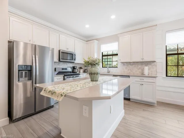 Kitchen featuring white cabinets, appliances with stainless steel finishes, a center island, and crown molding