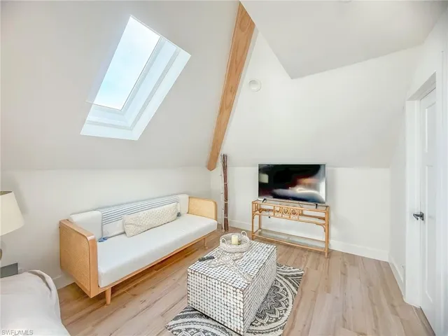 Living room with vaulted ceiling with skylight and light wood-type flooring