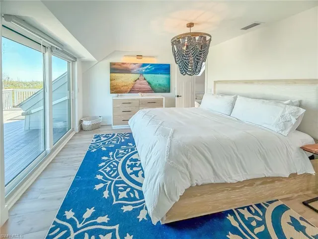 Bedroom with hardwood / wood-style flooring, access to outside, and a notable chandelier