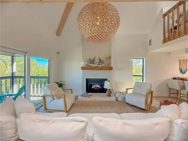Living room with beamed ceiling, hardwood / wood-style flooring, and a high ceiling