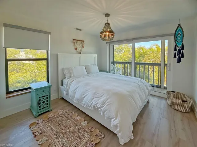 Bedroom featuring multiple windows, access to exterior, and light hardwood / wood-style floors