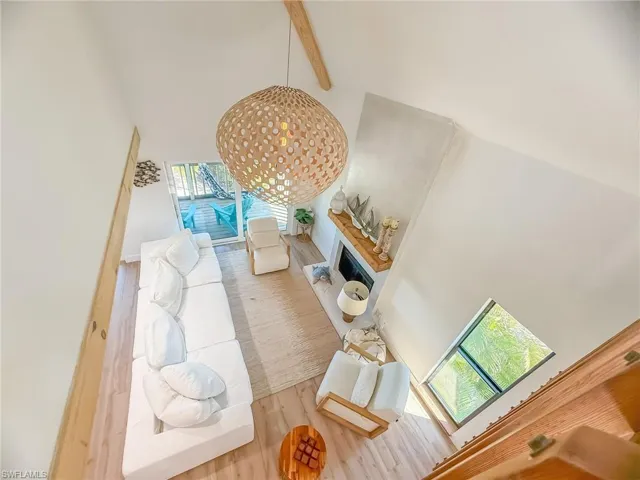 Living room with a high ceiling, hardwood / wood-style floors, beam ceiling, and a skylight