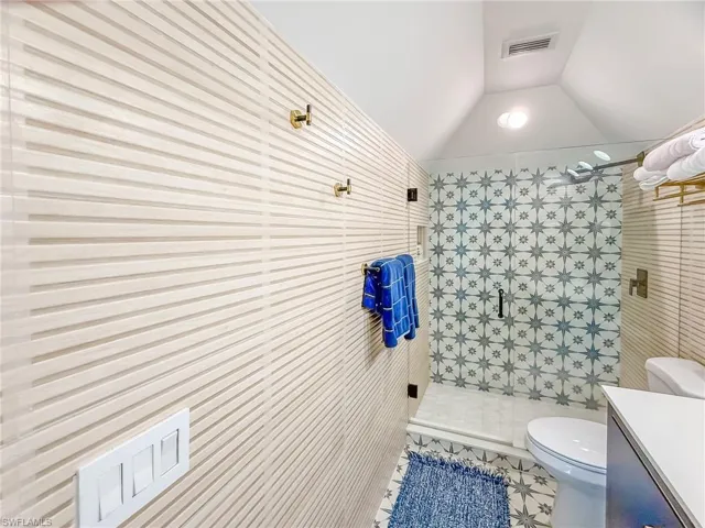 Bathroom with lofted ceiling, toilet, an enclosed shower, vanity, and tile patterned flooring