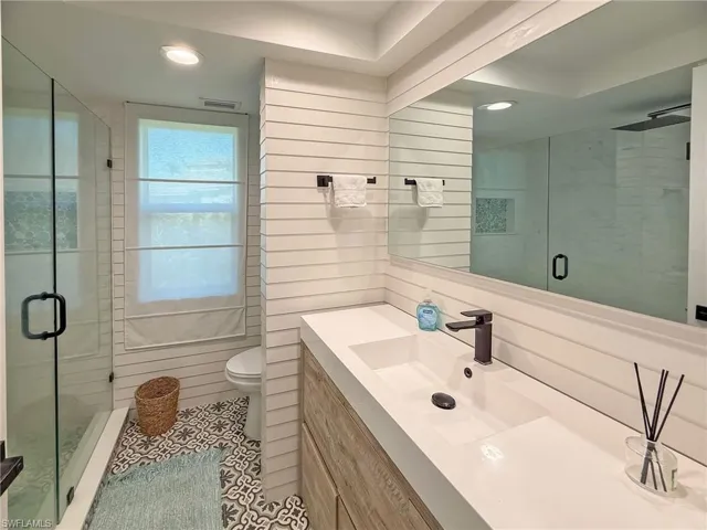 Bathroom featuring vanity, toilet, a shower with shower door, and tile patterned flooring