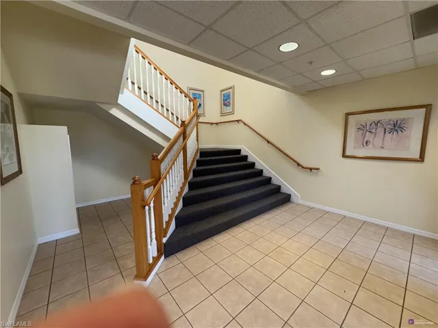 Stairs with a drop ceiling and tile patterned flooring