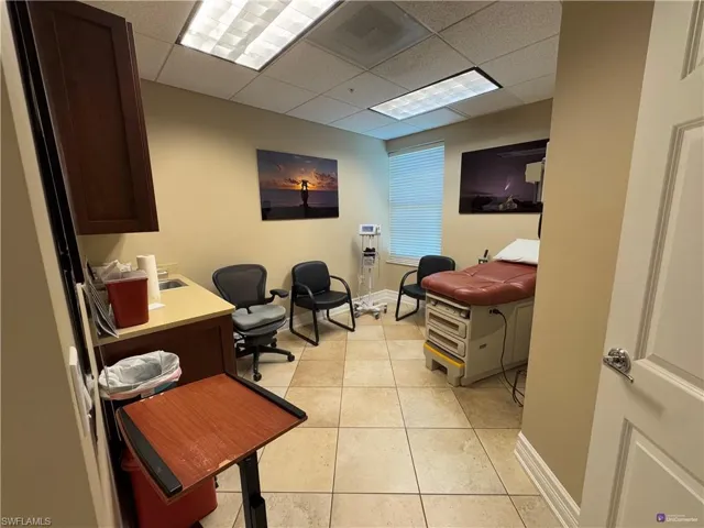 Office with a drop ceiling and light tile patterned flooring