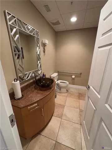 Bathroom with tile patterned floors, a drop ceiling, toilet, and vanity