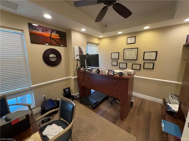 Office with a raised ceiling, ceiling fan, and dark wood-type flooring