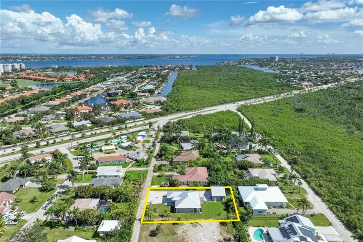 Aerial perspective of suburban area featuring a large body of water and property boundaries highlighted