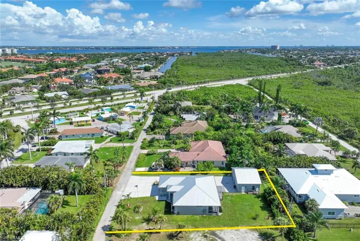 Aerial perspective of suburban area featuring property boundaries highlighted and a nearby body of water