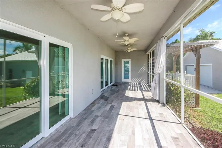 Unfurnished sunroom with ceiling fan, healthy amount of natural light, and wood finished floors