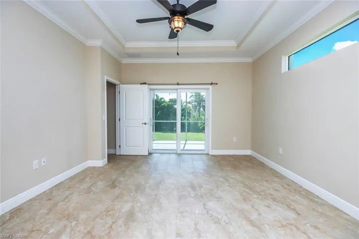 Empty room with healthy amount of natural light, ceiling fan, and crown molding
