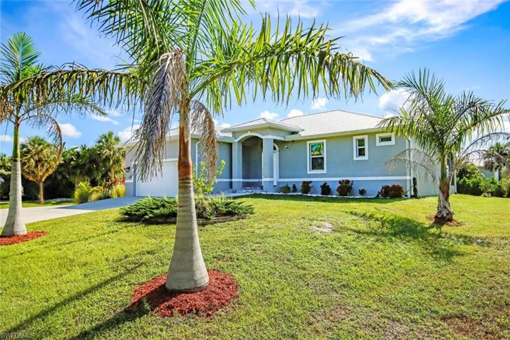 Ranch-style home with concrete driveway, an attached garage, stucco siding, a front yard, and a metal roof