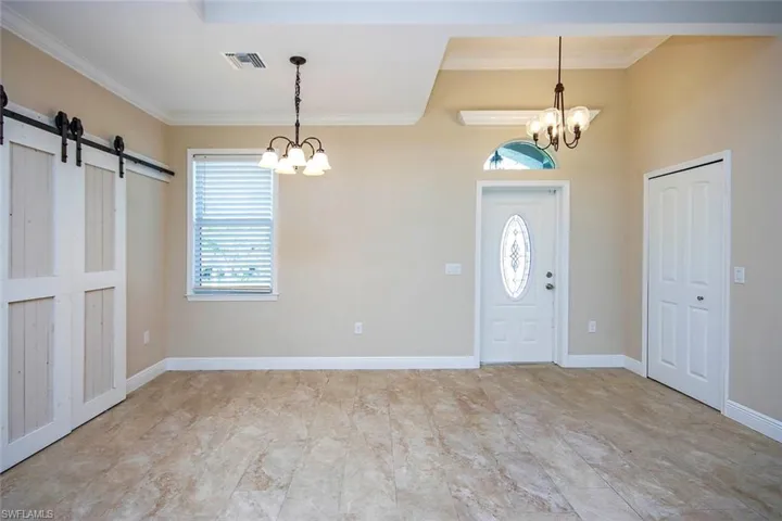 Entrance foyer featuring a barn door, a chandelier, healthy amount of natural light, and ornamental molding