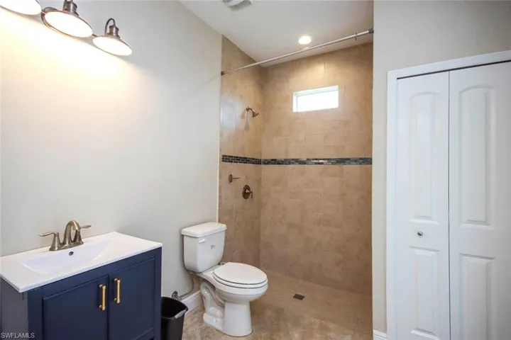 Bathroom featuring a closet, vanity, and tiled shower
