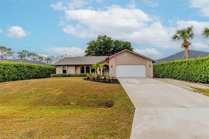 Ranch-style home featuring stucco siding, driveway, a front lawn, and an attached garage
