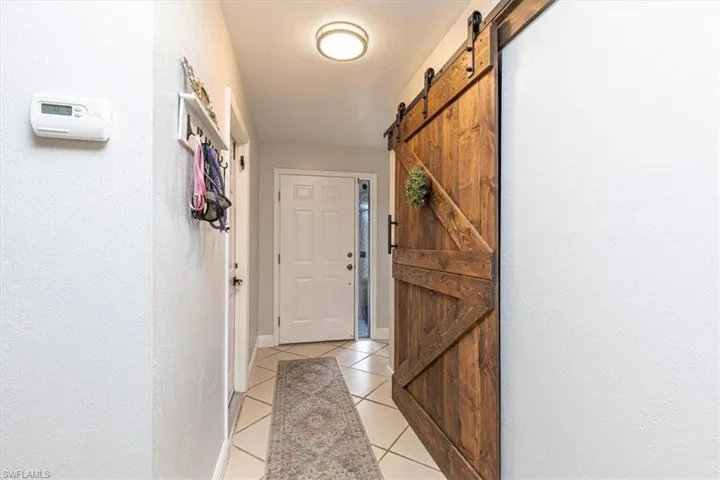 Hallway featuring a barn door, a textured wall, and light tile patterned floors