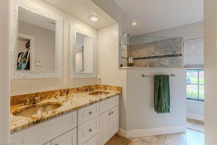 Full bath with double vanity, a spacious closet, recessed lighting, light tile patterned floors, and walk in shower