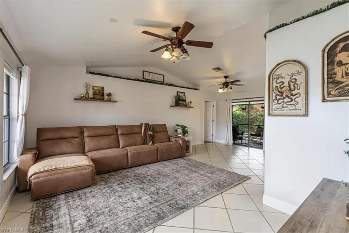 Living room with lofted ceiling, ceiling fan, and light tile patterned flooring