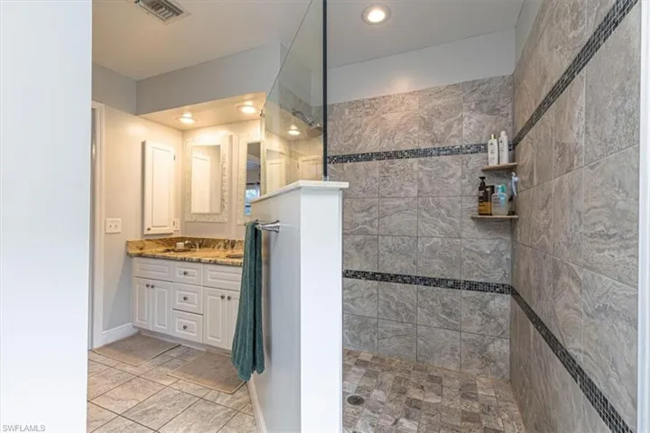 Bathroom featuring walk in shower, double vanity, and recessed lighting