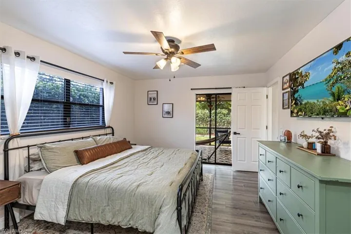 Bedroom with multiple windows, light wood-type flooring, access to exterior, and a ceiling fan