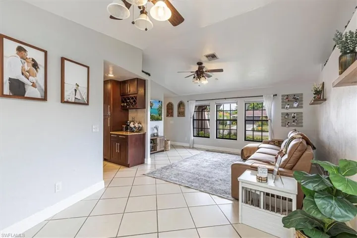 Living area featuring light tile patterned floors, vaulted ceiling, and ceiling fan