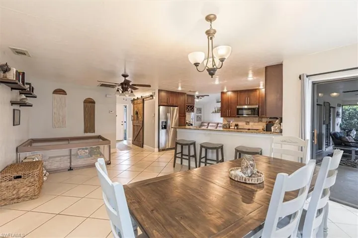 Dining room featuring light tile patterned floors, a barn door, and a ceiling fan