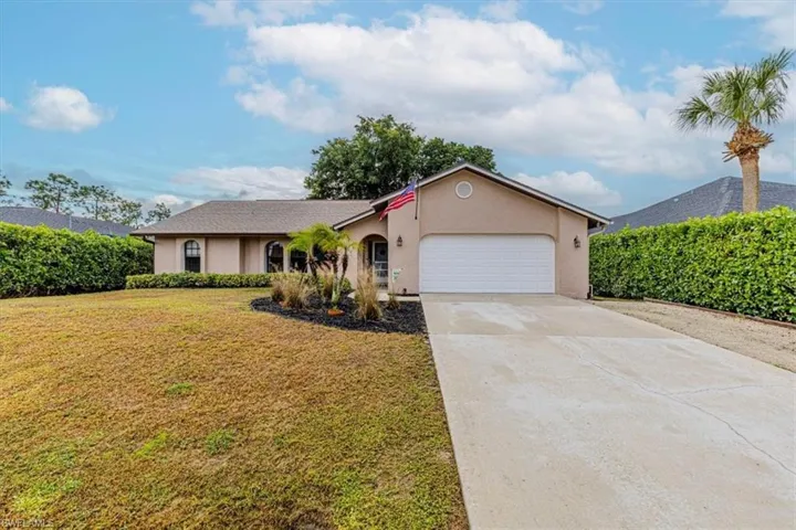 Ranch-style house featuring stucco siding, driveway, a front lawn, and an attached garage