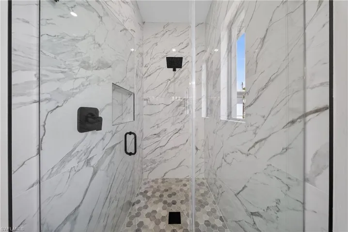 Full bathroom featuring double vanity and a marble finish shower