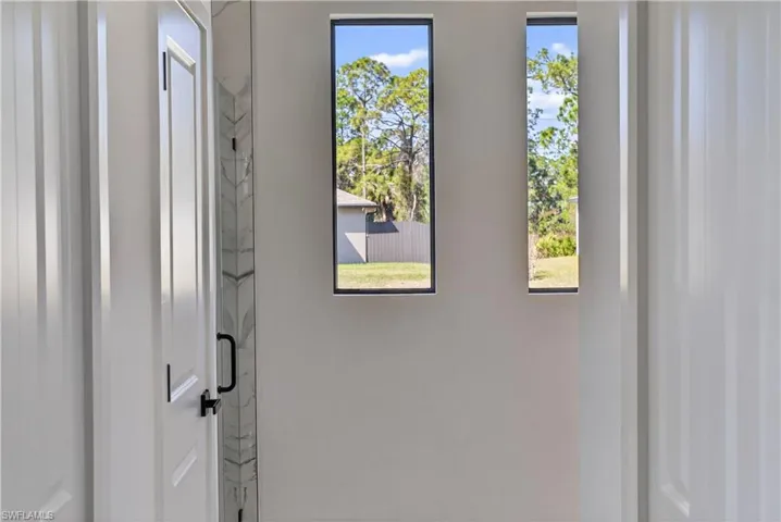 Hallway featuring light marble finish floors and baseboards