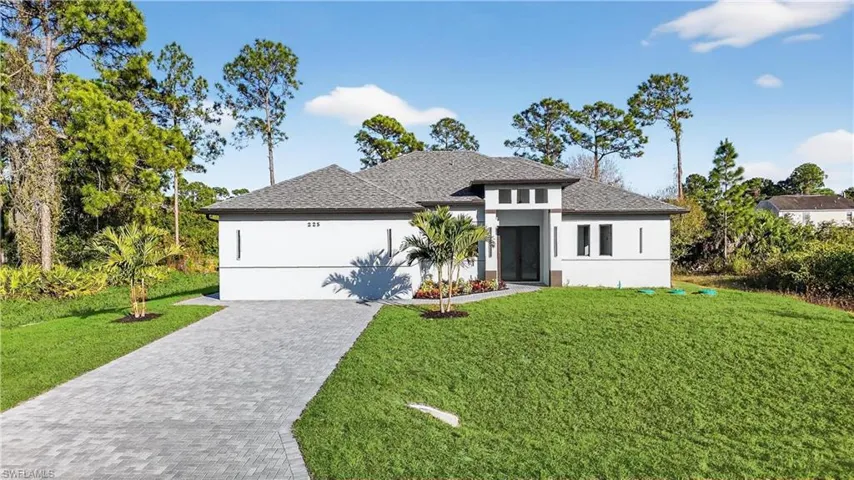 View of front of home featuring roof with shingles, a front lawn, and stucco siding