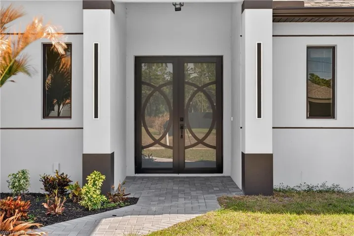 View of exterior entry featuring stucco siding, elevator, and a lawn