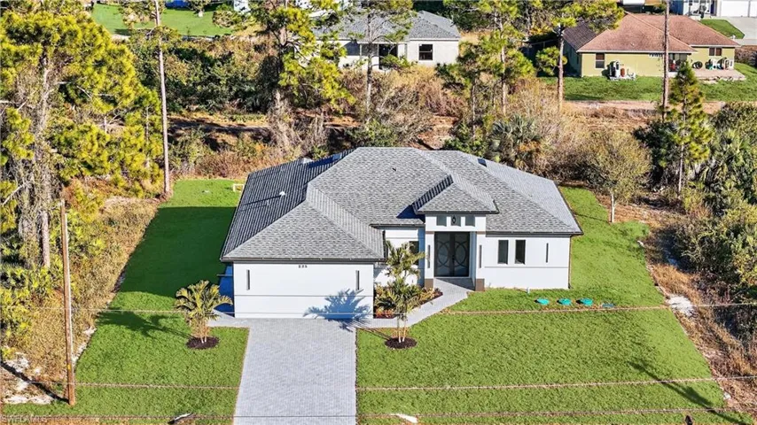 View of front of property with a front lawn, stucco siding, roof with shingles, and driveway